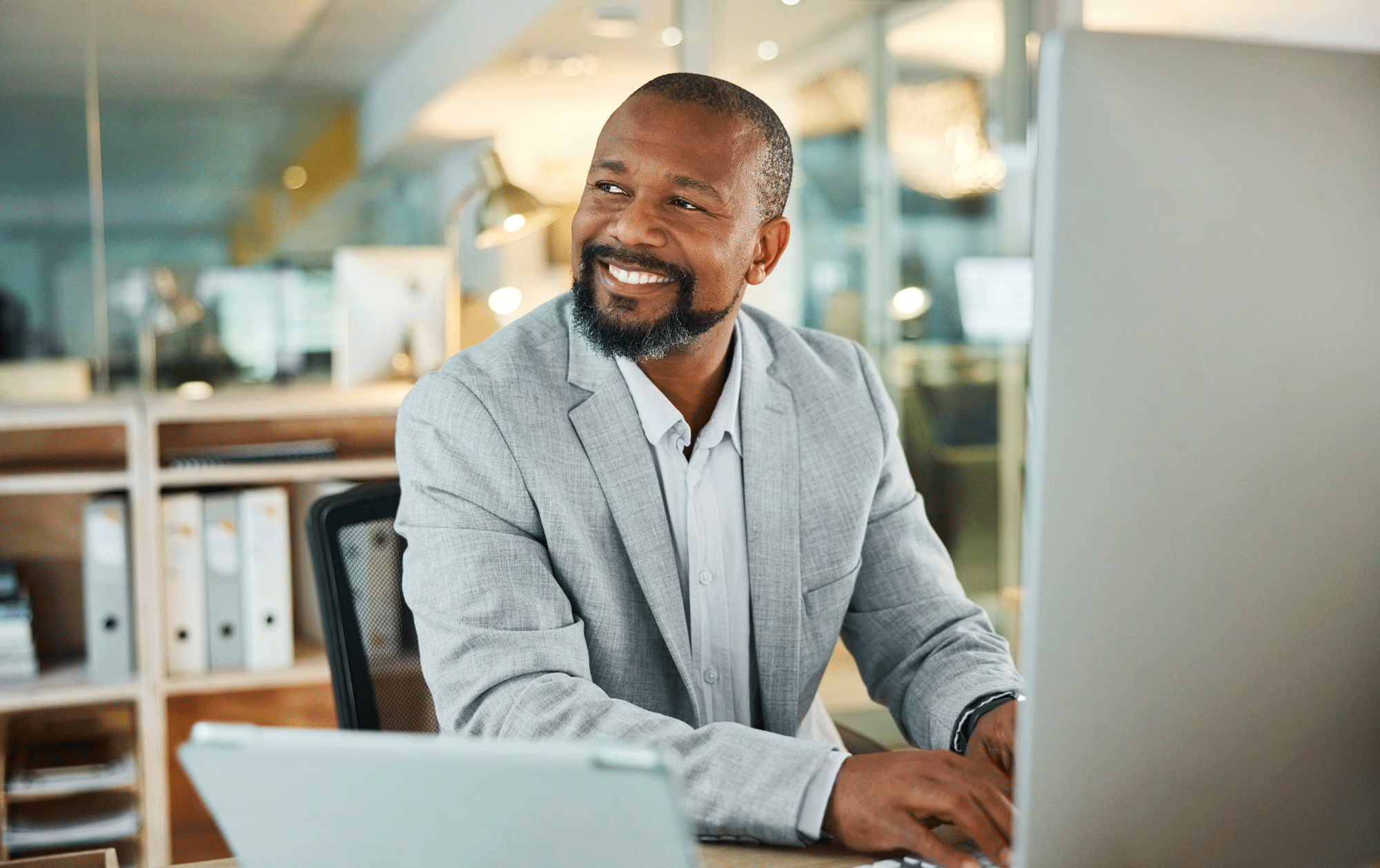 African American man in suit jacket smiling at computer.