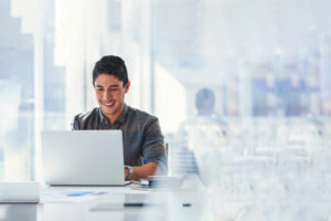 young man sitting at laptop in bright corporate office