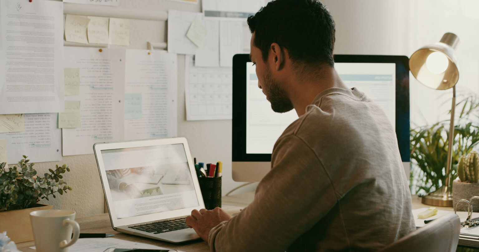 Younger male reviewing website on laptop