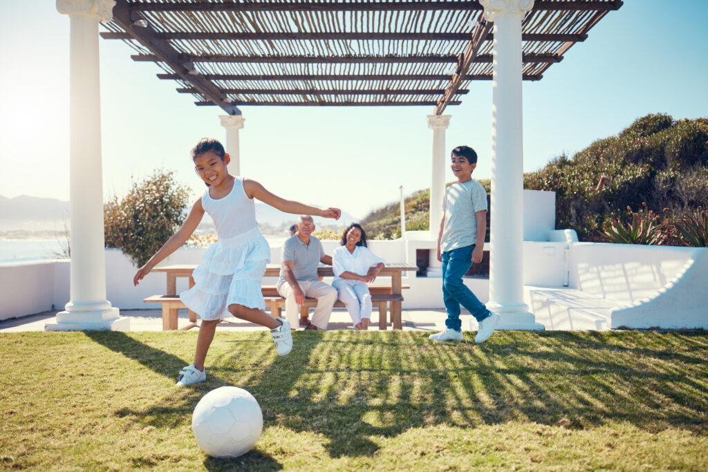 Family and children playing soccer on a lawn
