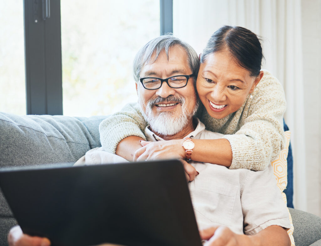 Senior couple on a sofa looking at a laptop to understand their rates