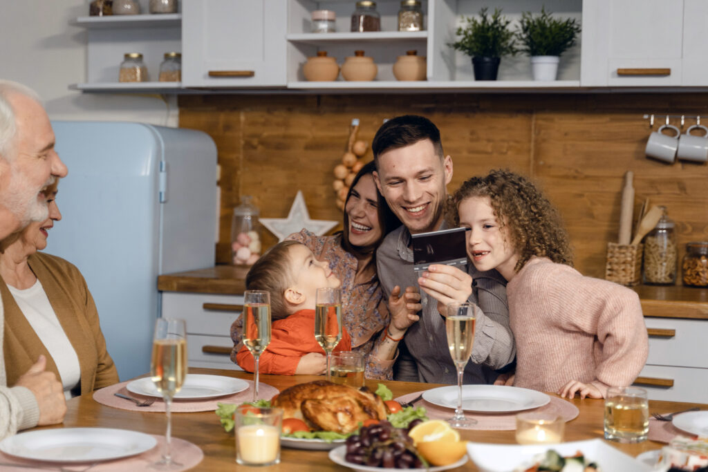 family eating dinner together and smiling at photo. parents hugging children.